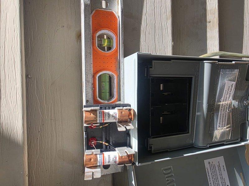 Completed air conditioning system installation with electrical disconnect box properly mounted and wired to exterior wall. Installed refrigerant line set with service valves, verified all copper connections, and ensured proper system startup with gauges attached for pressure testing.