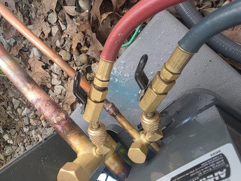 Completed air conditioning system installation with electrical disconnect box properly mounted and wired to exterior wall. Installed refrigerant line set with service valves, verified all copper connections, and ensured proper system startup with gauges attached for pressure testing.