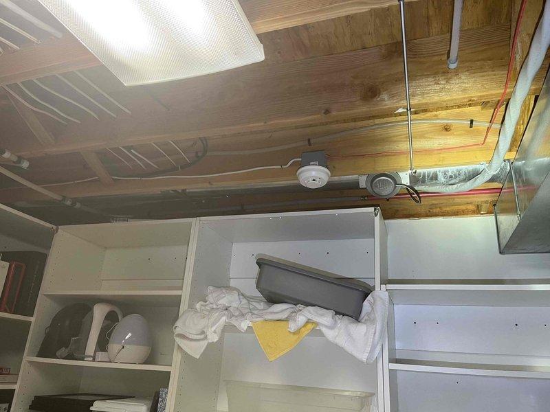 Responded to water leak in basement area beneath stairwell storage space. Upon inspection, identified moisture intrusion affecting wooden ceiling structure and shelving unit containing household items. Traced leak source to supply line connection serving upstairs bathroom fixtures. Tightened compression fitting on vertical copper pipe run visible in ceiling framing. Verified proper seal and tested system under pressure to confirm leak was stopped. Inspected adjacent bathroom plumbing including toilet supply line and connections - all found secure with no additional leaks detected. Advised customer to monitor area for recurrence and recommended placement of absorbent material to address residual moisture in affected storage space.