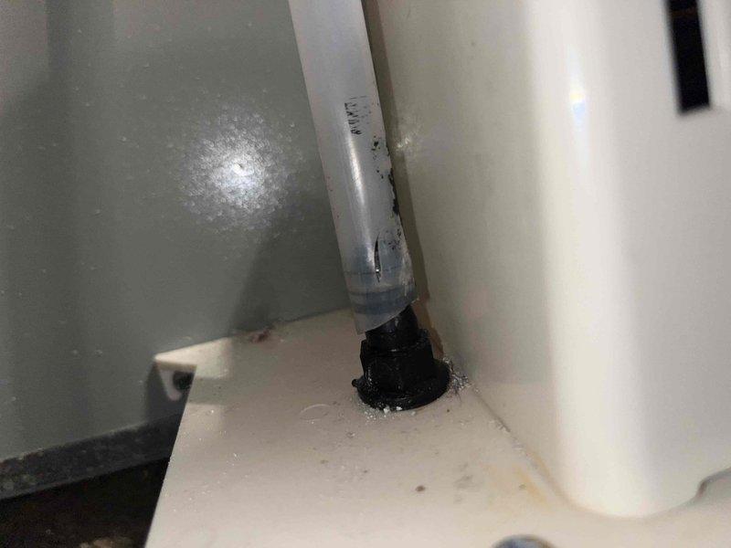 Responded to callback for leaking condensate tubing. Upon arrival, inspected the condensate drain system and confirmed water leakage at the base connection point where the PVC drain line passes through the unit floor. Secured the loose drain fitting and verified proper seal at the black grommet mounting point to eliminate the leak. Tested the condensate drainage system to confirm proper flow and verified no additional moisture present at the connection point.