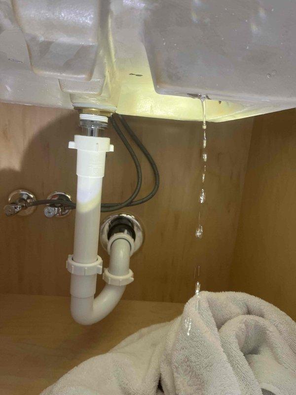Responded to service call reporting sewer gas odor throughout residence, incomplete toilet flushing, and non-operational sump pump. Upon inspection, discovered multiple plumbing issues including a leaking sink drain connection with visible water damage and staining at the basin interface. Identified standing water with rust-colored contamination in HVAC condensate drain pan, indicating drainage system complications. Addressed water intrusion issues and restored proper drainage function to affected plumbing systems.