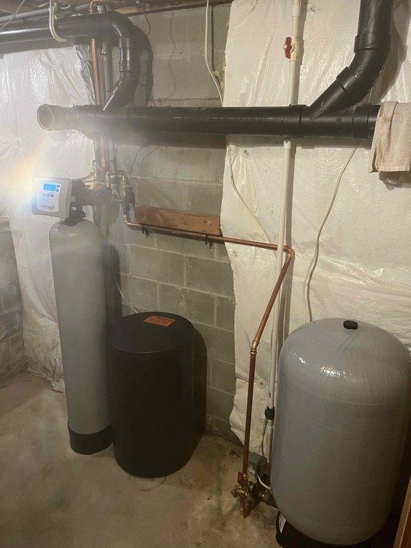 # No Water Service Call

Responded to complete loss of water throughout 27-year-old residential property. Homeowner reported intermittent water supply failure several days prior with temporary restoration, followed by total system shutdown. Upon arrival, conducted comprehensive assessment of basement mechanical room housing water treatment infrastructure.

## Inspection Findings

Inspected dual-tank water treatment system consisting of white softener tank with digital control head and secondary black treatment tank. Evaluated extensive overhead plumbing network with black insulated supply lines and copper distribution piping. Examined gray expansion tank and associated pressure components. Control panel on primary treatment tank displayed operational status indicators.

## Diagnostic Procedures

Tested incoming water supply pressure and flow rates. Verified municipal water service continuity at main shutoff. Assessed water softener regeneration cycle functionality and timer settings. I
