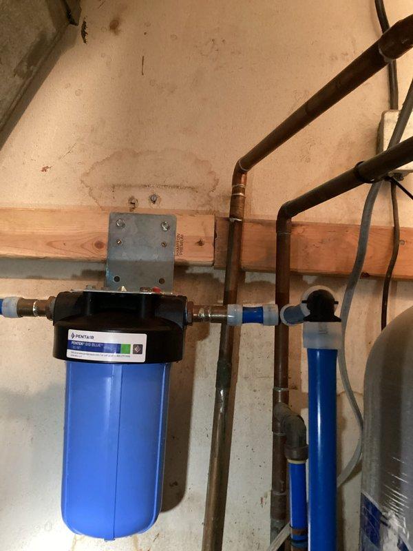 Completed filter replacement inside water softener brine tank and performed comprehensive system inspection as part of renewal club maintenance. The multi-stage water treatment system, including blue filter housing and connected components with copper piping, was evaluated for proper operation and water quality performance. All filtration components were assessed and replaced as needed to ensure optimal water softening and treatment efficiency.