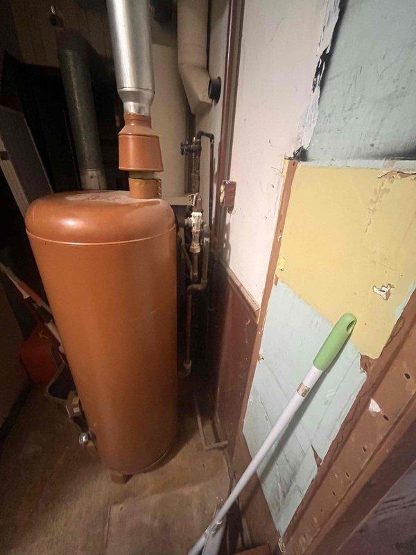 Conducted site evaluation of existing boiler system in basement utility area for potential replacement with wall-mounted unit to accommodate upcoming kitchen remodel. Assessed current installation including expansion tank, copper piping configuration, and mechanical components to determine space requirements and feasibility for either combination boiler or tankless water heater installation. Documented existing equipment layout and mechanical room conditions, noting aged HVAC system components and available clearances for wall-mounted unit placement.