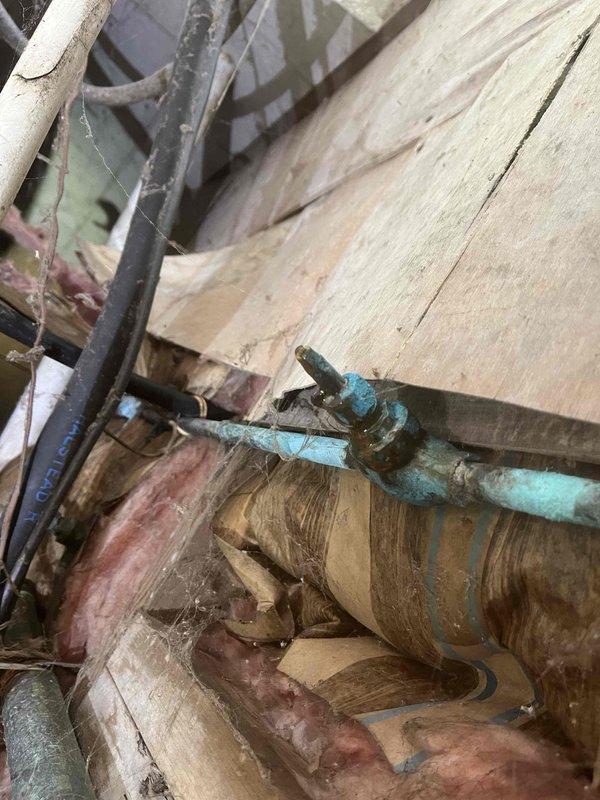 Responded to low water pressure emergency call where customer experienced sudden pressure loss during shower use accompanied by unusual pump noise. Upon arrival, performed diagnostic testing of well pump system using digital clamp meter, which revealed abnormal electrical readings of 343 volts, indicating potential power supply issues affecting pump performance. Inspected water supply infrastructure in crawl space and identified severely corroded copper piping with heavy turquoise-green patina buildup that could contribute to flow restriction. Documented existing conditions of plumbing system including deteriorated pipe sections and mounting hardware for recommended repairs to restore proper water pressure and prevent future system failure.
