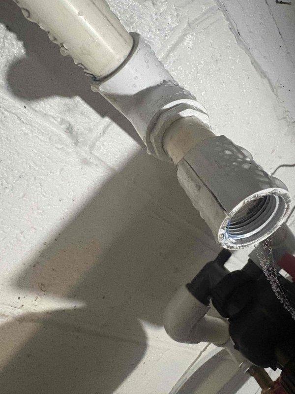 Responded to emergency call for newly installed well pump system failure that caused water discharge into basement. Upon arrival, assessed damaged piping connections and identified compromised PVC joints that resulted in system breach. Shut off water supply, drained affected lines, and inspected full extent of leak damage. Reinstalled and properly secured white PVC water supply piping with correct fittings and couplings. Replaced brass hose bib assembly with 90-degree elbow configuration and installed red-handled shut-off valve for system isolation. Verified all pipe connections were properly sealed and pressure-tested system to ensure no additional leaks. Confirmed proper operation of well pump system and restored water service to residence.