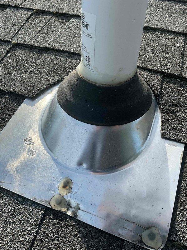 Responded to callback regarding water intrusion at roof penetration where previous ductwork modification was completed. Met with roofing contractor on-site to assess flashing integrity around PVC pipe penetration through asphalt shingle roof. Documented existing conditions with photographs showing metal flashing assembly with aluminum base plate and conical boot seal around white PVC duct penetration. Observed weathering and discoloration on flashing components and rubber gasket seal. Coordinated with roofing contractor to determine if roof-related repairs are needed and documented conditions for further review.