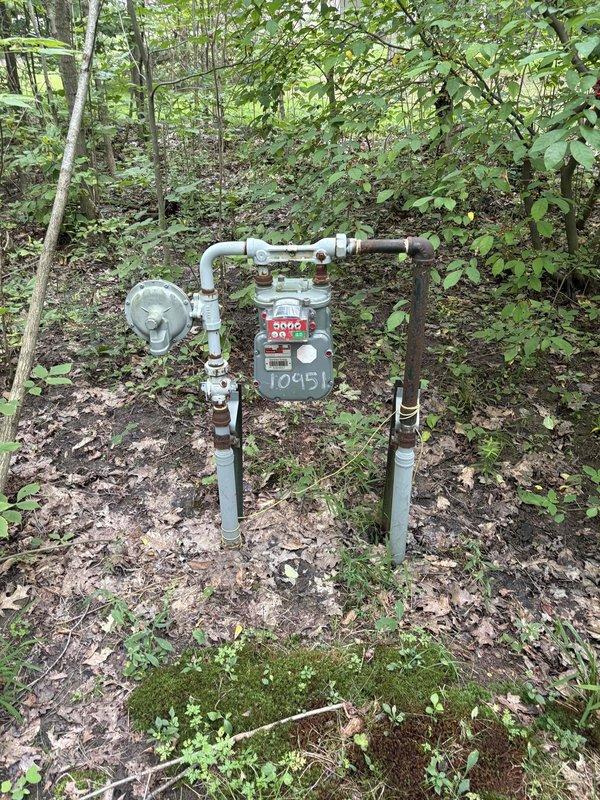 Conducted site assessment for new gas line installation to service an incoming pool heater at property with no existing gas infrastructure for pool equipment. Evaluated existing natural gas meter assembly located in wooded area of property, documenting current gas service configuration including meter, pressure regulator, and existing piping system. Assessed routing requirements and feasibility for extending gas line from meter location to future pool heater installation site. Photographed existing gas meter setup showing meter number, regulator valve, and pipe connections to establish baseline conditions for estimate preparation. Awaiting pool heater specifications from customer to finalize gas line sizing, materials list, and installation scope for new dedicated gas service line.