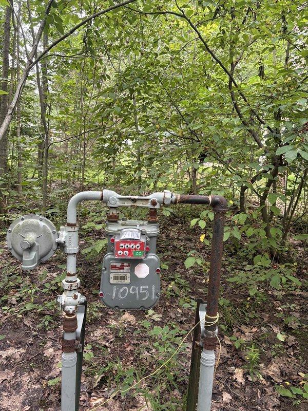 Conducted site assessment for new gas line installation to service an incoming pool heater at property with no existing gas infrastructure for pool equipment. Evaluated existing natural gas meter assembly located in wooded area of property, documenting current gas service configuration including meter, pressure regulator, and existing piping system. Assessed routing requirements and feasibility for extending gas line from meter location to future pool heater installation site. Photographed existing gas meter setup showing meter number, regulator valve, and pipe connections to establish baseline conditions for estimate preparation. Awaiting pool heater specifications from customer to finalize gas line sizing, materials list, and installation scope for new dedicated gas service line.
