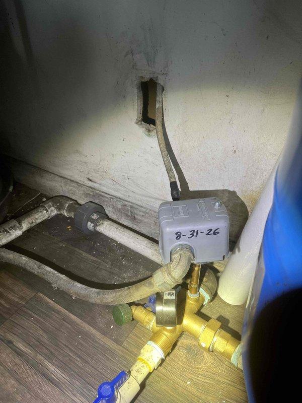 Completed return service for a previously sold 1/2HP well pump installation. Inspected the pump system and associated components located in the crawl space area beneath the structure. Verified proper operation of the well pump unit and examined all plumbing connections, electrical controls, and gas line components in the utility space. The installation includes a brass gas valve assembly with yellow fittings, blue ball valve control, and gray electrical switch with service date notation. All refrigerant lines, insulated piping, and conduit penetrations through the foundation were checked for secure mounting and proper function. System is operating within normal parameters with all connections secure and no leaks detected.