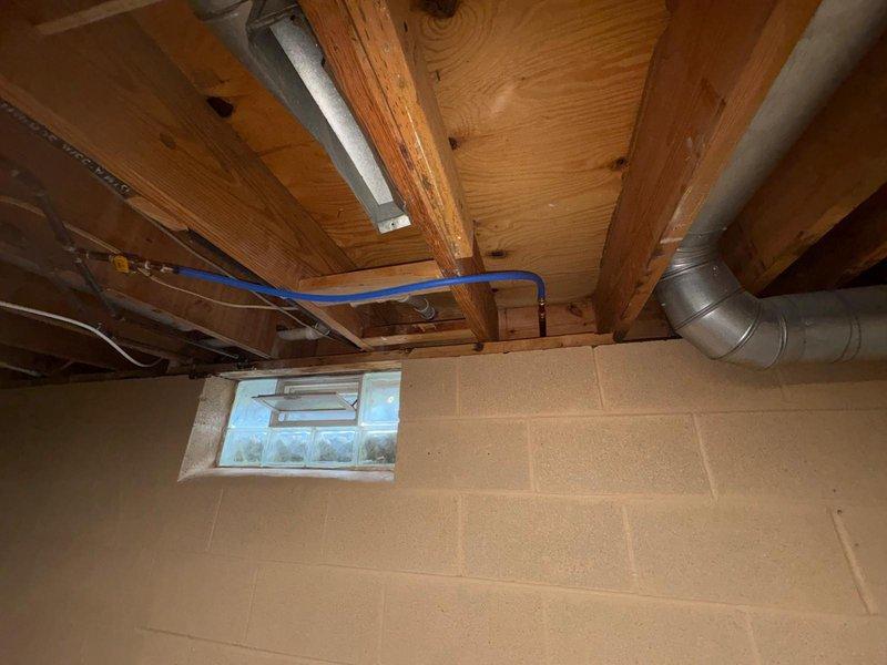 Returned to property to complete plumbing repair work that was previously sold and authorized. Upon arrival, accessed basement crawl space to inspect and address plumbing system concerns. Located and evaluated blue PEX water line routing along ceiling joists in basement area near concrete block foundation wall. Documented existing conditions including pipe placement, support structure, and connection points. Verified proper installation of PEX piping system and confirmed secure mounting to floor joists. Inspected surrounding mechanical systems including ductwork and electrical conduit for clearance and code compliance. Examined concrete block foundation wall for any signs of moisture intrusion or water damage related to plumbing system. Noted minor surface staining on exterior block wall and verified no active leaks or plumbing-related issues contributing to discoloration. Completed final inspection of all accessible plumbing components in basement space. All work performed in accordan