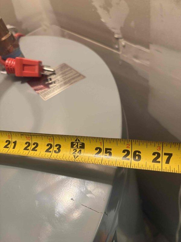 Responded to emergency call for catastrophic gas water heater failure that resulted in tank rupture through drywall and active flooding. Immediately shut off gas supply and water supply to compromised unit to prevent further damage and ensure safety. Documented equipment failure including measurements of damaged 24-inch diameter cylindrical water heater tank and photographed existing pressure tank system with dual black cylindrical vessels, copper piping, pressure gauge, and associated plumbing components. Customer contacted insurance company for claim processing due to extent of property damage from water heater explosion.