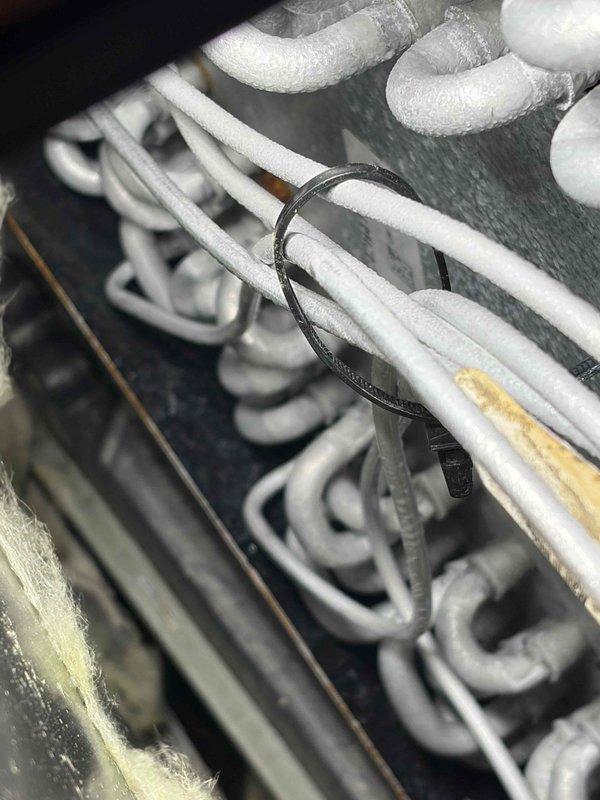 Responded to recurring AC alarm on 5-year-old outdoor unit. Upon inspection, discovered extensive frost and ice buildup on evaporator coil assembly, indicating restricted airflow or refrigerant issue. Found insulated refrigerant lines properly secured but system experiencing freezing condition similar to previous service call. Documented frost accumulation covering serpentine coil pattern throughout heat exchanger. Photographed affected components showing thick white frost coating on coil surfaces and refrigerant line routing. System requires further diagnosis to determine root cause of recurring freeze-up condition, likely related to airflow restriction, refrigerant charge imbalance, or metering device malfunction that was not fully resolved during previous repair.