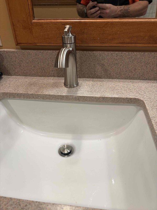 Completed installation of primary bathroom sink and faucet assembly as part of pre-sold repair project. Installed white rectangular undermount basin into existing laminate countertop with brushed stainless steel single-handle faucet, including complete drain assembly with chrome tailpiece and white PVC P-trap configuration. Connected braided stainless steel supply lines to shut-off valves and verified all plumbing connections for proper operation and leak-free performance.