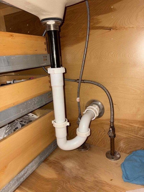 Completed installation of primary bathroom sink and faucet assembly as part of pre-sold repair project. Installed white rectangular undermount basin into existing laminate countertop with brushed stainless steel single-handle faucet, including complete drain assembly with chrome tailpiece and white PVC P-trap configuration. Connected braided stainless steel supply lines to shut-off valves and verified all plumbing connections for proper operation and leak-free performance.