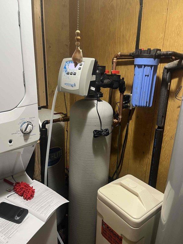 Responded to no water complaint at residential property. Upon inspection, discovered water treatment system with severe fire and heat damage affecting primary supply lines. Multiple copper supply pipes showed extensive corrosion, melting, and oxidation with characteristic green patina from extreme heat exposure. Electrical wiring to system controls exhibited burn damage with exposed sections. Water softener tank and associated components compromised by fire damage in utility area. Documented existing conditions showing charred wall surfaces, damaged piping infrastructure, and debris accumulation. System rendered inoperable due to extent of fire damage requiring complete replacement of affected plumbing components and water treatment equipment to restore water service.