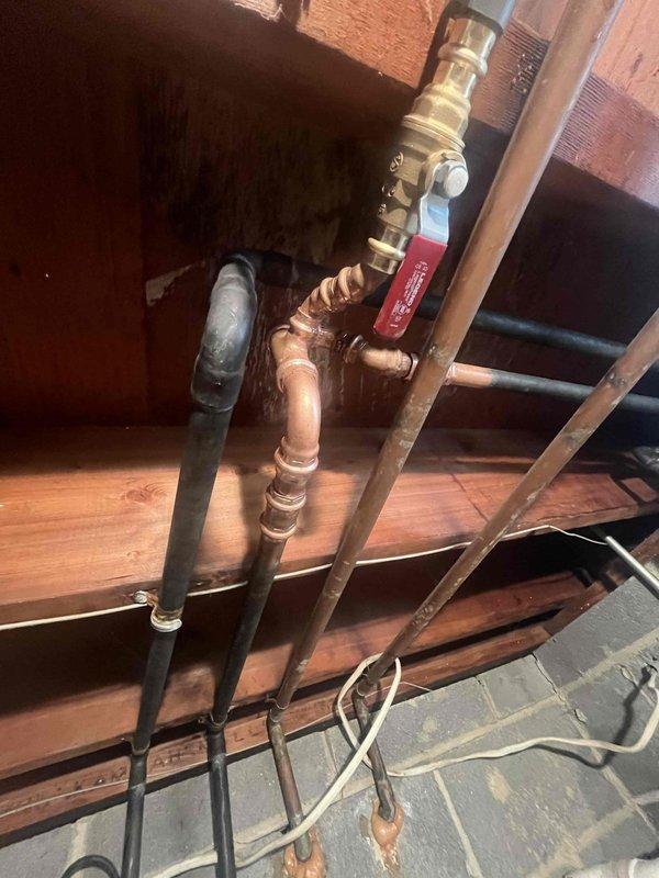 Replaced defective shut-off valves in basement water supply system. Installed new brass ball valves with red handles on parallel copper supply lines mounted to concrete block wall, ensuring proper shutoff capability for the building's water distribution system.