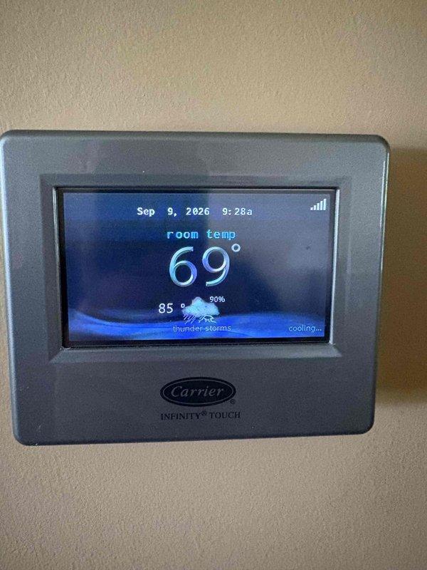 Responded to service call for non-operational air conditioning system affecting cooling capability. Upon arrival, evaluated existing ten-year-old AC system and associated equipment including Carrier Infinity Touch thermostat control and basement-installed ductwork configuration. Documented current system conditions through photographic assessment of HVAC equipment installation, including metal ductwork, control housing, and thermostat interface displaying active cooling mode at 69° room temperature. Provided comprehensive estimate for complete system replacement based on equipment age and operational status.