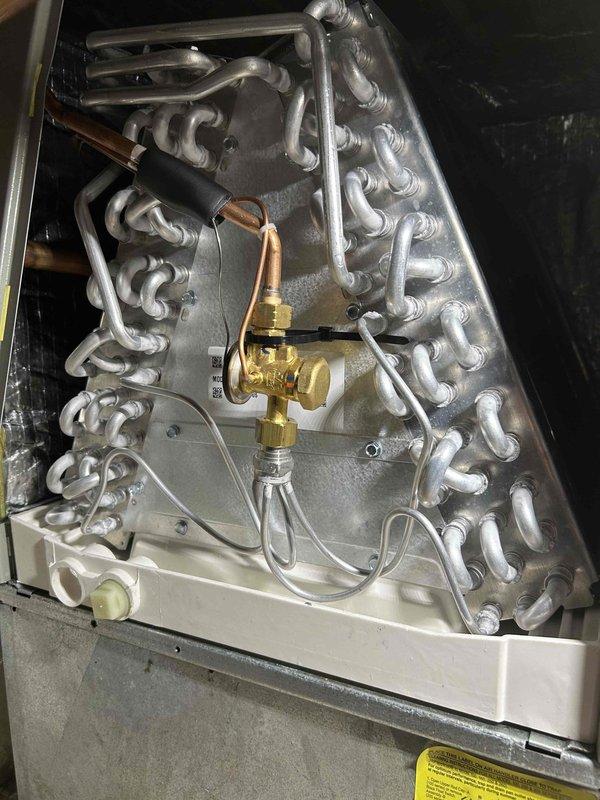 Performed return air zone inspection and system evaluation. Documented internal HVAC components including evaporator coil assembly, refrigerant lines, and metering device. Captured images of serpentine coil configuration with brass expansion valve and capillary tube sensing element for service records. All copper refrigerant lines and electrical connections verified to be properly secured within unit cabinet.