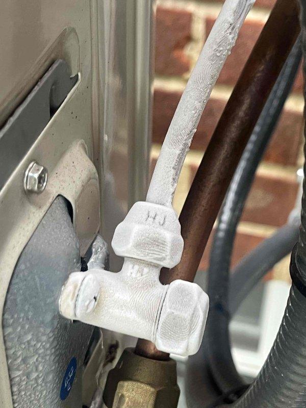Responded to callback for mini split system installed approximately one year ago displaying OU error code with complete system failure. Upon arrival, verified error code on remote control and inspected outdoor unit connections. Identified frost accumulation on refrigerant lines and suction line service port, indicating possible refrigerant flow restriction or low charge condition. Photographed remote displaying error code and inspected line set connections at outdoor unit. System evaluated for potential refrigerant leak, restriction in refrigerant circuit, or electronic control malfunction causing the OU fault code.