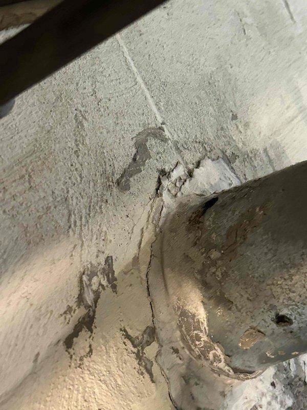 Responded to service call for hydronic boiler system with corroded vent pipe. Upon inspection, discovered severe deterioration of vent pipe extending to wall penetration point, with significant corrosion visible at pipe opening and rim showing rust-colored oxidation and material breakdown. Documented existing conditions including compromised pipe integrity, crumbling edges, and internal buildup. Observed structural concerns at wall junction where vent pipe meets masonry, noting cracked cinder block and deteriorated joint material. Photographed damage for assessment and provided recommendations for vent pipe replacement and evaluation of chimney liner condition before proceeding with repairs.