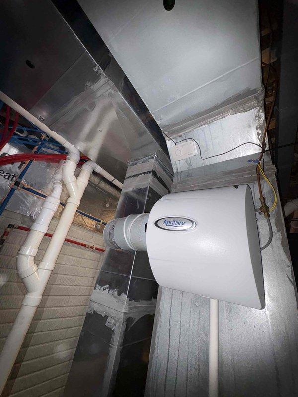 Completed comprehensive estimate for proactive replacement of 14-year-old air conditioning system and furnace located in basement mechanical room. Evaluated existing vertical furnace configuration with integrated Aprilaire humidifier, assessed current ductwork infrastructure including metal supply and return ducts, and documented white PVC drainage lines and electrical connections. Photographed equipment layout, clearances, and access points to develop accurate replacement specifications for both heating and cooling systems.