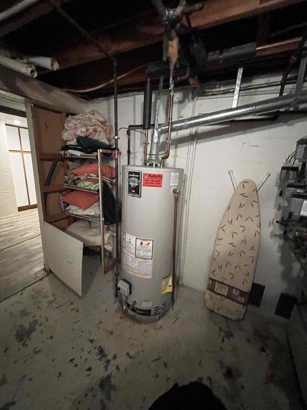 Responded to basement water pooling complaint and conducted thorough inspection of utility area. Examined water heater, surrounding plumbing connections, and overhead pipe infrastructure for signs of active leaks or moisture intrusion. Inspected concrete floor staining patterns and monitored for active water accumulation. Documented conditions with photos showing water heater installation, ceiling plumbing runs, and basement storage area. Tested and verified moisture detection equipment functionality. No active water source identified during inspection period; recommended continued monitoring of area for recurrence of puddling conditions.
