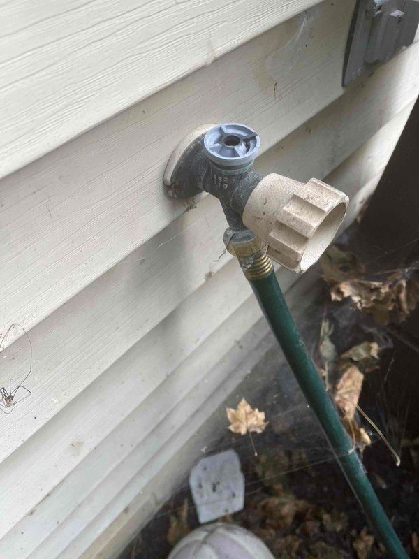 Replaced outdoor hose bib that had seized threads preventing hose removal. Removed the fused spigot assembly from the exterior wall, installed new brass hose bib with proper threading, and verified operation with no leaks detected upon testing.