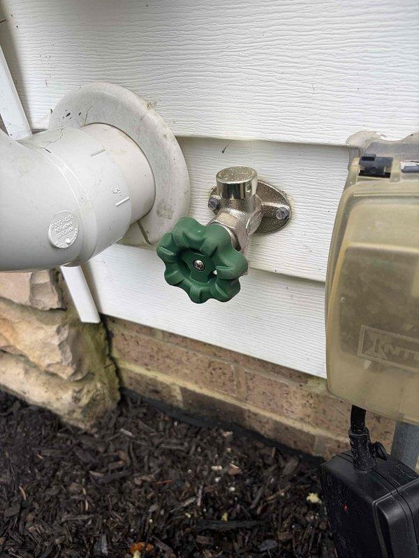 Completed return visit to finalize hose spigot installation previously sold. Installed exterior frost-free hose bib with green wheel handle valve mounted to white vinyl siding, connected to white PVC supply line with proper elbow fittings. Verified interior basement connections to existing plumbing system, ensuring all joints and fittings were secure and leak-free. Tested water flow and shutoff functionality at both the exterior spigot and interior supply connections. All components installed to code and system operating properly.