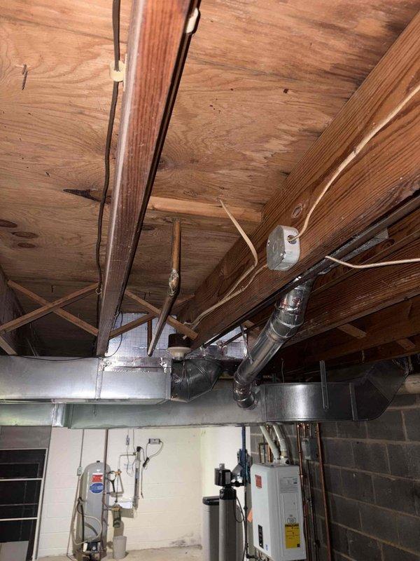 Conducted site assessment for relocation of existing baseboard heater in basement utility area. Evaluated current HVAC infrastructure including exposed ductwork, air handler unit, and existing heating distribution system. Documented mechanical room layout with exposed ceiling joists, concrete block walls, and existing utility connections including PVC piping and electrical systems. Photographed current baseboard heater location and surrounding mechanical equipment to prepare estimate for repositioning work.