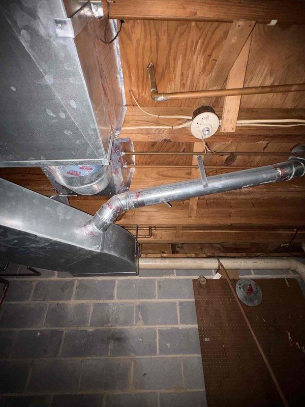 Conducted site assessment for relocation of existing baseboard heater in basement utility area. Evaluated current HVAC infrastructure including exposed ductwork, air handler unit, and existing heating distribution system. Documented mechanical room layout with exposed ceiling joists, concrete block walls, and existing utility connections including PVC piping and electrical systems. Photographed current baseboard heater location and surrounding mechanical equipment to prepare estimate for repositioning work.