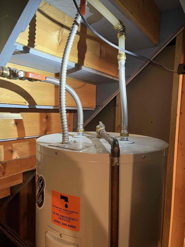 Returned to property to complete previously sold anode rod replacement on residential water heater located in basement utility area beneath staircase. Successfully removed old anode rod and installed new copper anode rod assembly with hexagonal cap, ensuring proper threading and secure connection to extend water heater life and prevent tank corrosion.