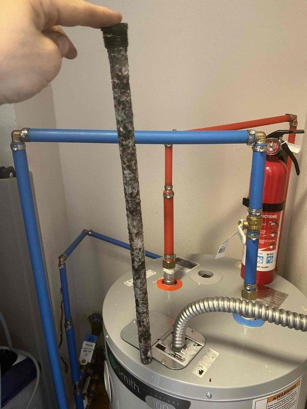 Performed complete tank flush on residential water heater due to customer complaint of foul-smelling water. Upon inspection, discovered significant sediment accumulation at bottom of tank. Drained unit completely and flushed system multiple times until water ran clear. Removed and displayed sediment filter showing substantial dark granular debris that had collected in the system, confirming the source of the odor issue. Verified all connections, including PEX manifold system and relief valve, remained secure throughout the procedure. Refilled tank, checked for proper operation, and confirmed water quality improvement. System restored to normal function with odor issue resolved.