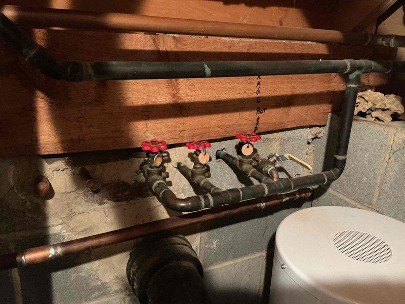 Responded to service call regarding abnormally high water bill and suspected leak. Performed comprehensive inspection of plumbing system including basement manifold distribution system with multiple zone control valves and main water supply lines. Documented existing plumbing configuration featuring copper piping, red-handled shut-off valves, and multi-zone manifold system controlling various fixtures throughout the property. Visual inspection completed of all accessible water lines, connections, and valve assemblies to identify potential leak sources contributing to elevated water consumption.
