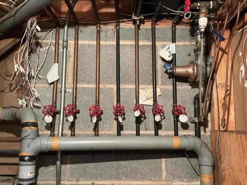 Responded to service call regarding abnormally high water bill and suspected leak. Performed comprehensive inspection of plumbing system including basement manifold distribution system with multiple zone control valves and main water supply lines. Documented existing plumbing configuration featuring copper piping, red-handled shut-off valves, and multi-zone manifold system controlling various fixtures throughout the property. Visual inspection completed of all accessible water lines, connections, and valve assemblies to identify potential leak sources contributing to elevated water consumption.