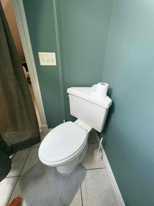 Responded to water leak complaint in basement below bathroom area. Upon inspection, examined bathroom fixtures and flooring for signs of water infiltration. Investigated toilet, flooring, and surrounding areas as potential leak sources. Documented conditions with photographs showing bathroom layout, toilet installation, and floor surfaces with visible staining patterns near toilet base and along baseboards, which may indicate chronic moisture issues or previous water events requiring further investigation of shower pan integrity and drain connections.