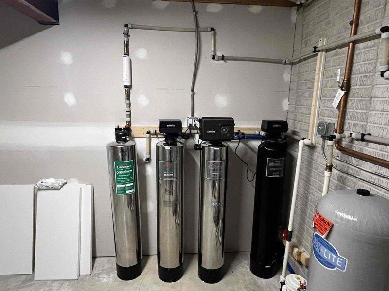 Serviced existing water treatment system consisting of multiple filtration tanks and control valves. Replaced depleted chlorine tablets in chlorination unit to address returning odor issues in water supply. System inspected and confirmed operational after tablet replacement.