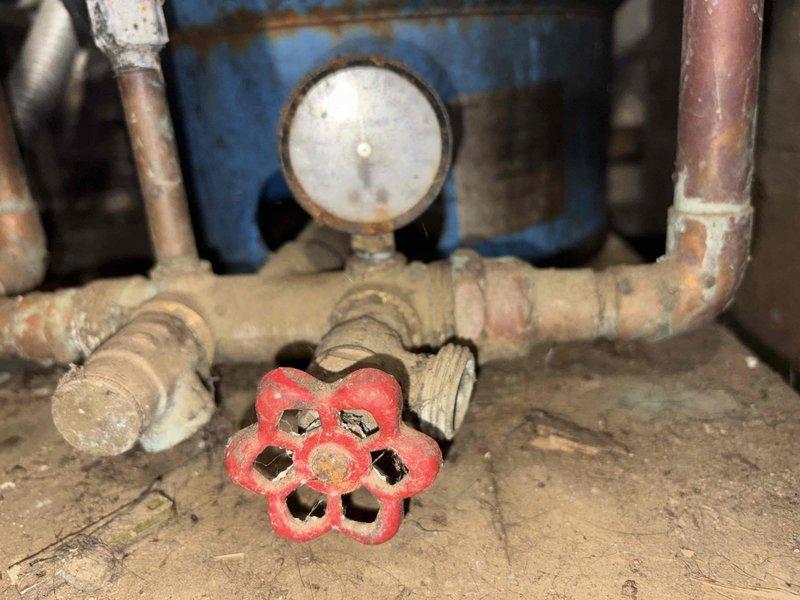 Responded to customer complaint of water softener malfunction, changes in water quality, and iron odor. Upon inspection, discovered severely corroded plumbing infrastructure including deteriorated metal pipes, aged pressure tank components, and compromised valve assemblies throughout the water treatment system. The extensive rust and corrosion on the Well-X-Trol pressure tank, connecting pipes, and control valves indicated long-term moisture exposure and system degradation affecting water softener performance. Documented existing conditions including failed pressure gauge, corroded valve mechanisms, and deteriorated copper piping. Advised customer that the iron smell and water quality issues stem from the corroded metal components leaching into the water supply, and that comprehensive system replacement of the pressure tank, valves, and associated piping is necessary to restore proper water treatment functionality and eliminate odor concerns.