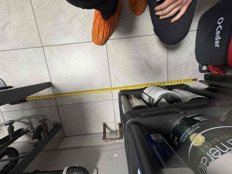 Completed rough-in measurements and site assessment for toilet installation requiring concrete demolition. Measured spacing between existing copper supply lines protruding from floor to ensure proper fixture placement and compliance with plumbing code requirements for new toilet rough-in.