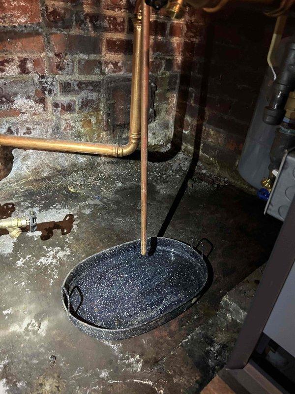 Responded to reported leak on Weil-McLain boiler system. Upon inspection, discovered active water infiltration affecting boiler piping and surrounding basement area. Evidence of chronic moisture issues present, including significant efflorescence on masonry walls and standing water on concrete floor. Investigated leak source at copper piping connections and boiler base, collected sediment samples from system for analysis. Documented conditions with photographs showing deteriorated basement environment, compromised drain pan positioning beneath vertical copper supply lines, and mineral deposits indicating long-term water exposure. Recommended immediate repair of identified leak points and comprehensive moisture remediation to prevent further system damage and maintain safe operating conditions.