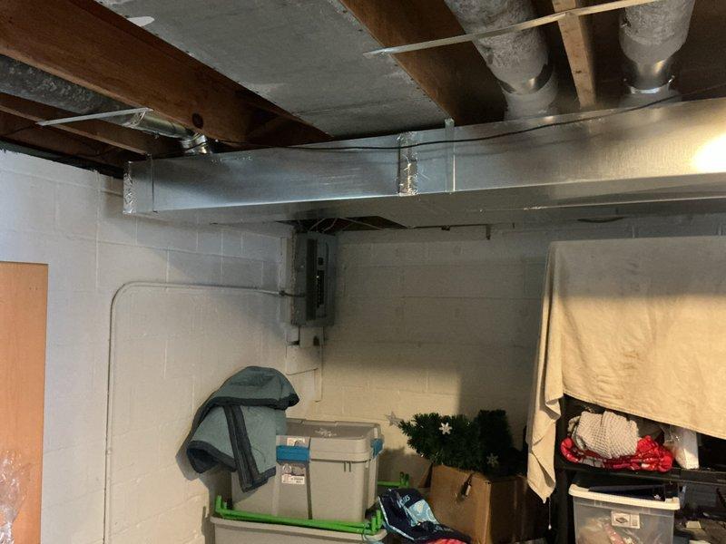 Completed return ductwork installation in basement area as part of same-day HVAC system installation. Installed rectangular metal supply ductwork with proper support from existing floor joists, ensuring secure mounting and proper airflow pathway. Verified system performance using digital thermometer, confirming temperature differential readings of 51.8°F and 116.1°F at measurement points to validate proper system operation and air distribution.