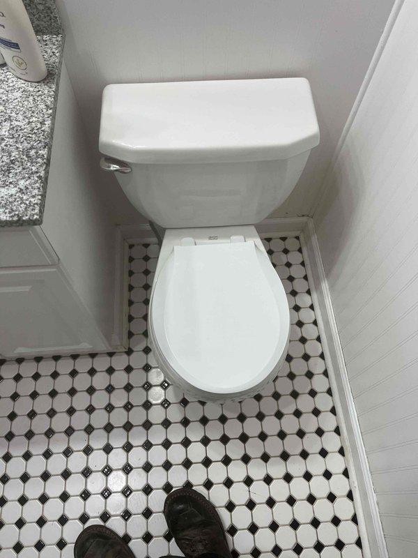 Responded to report of water leaking into basement during toilet flushing. Upon inspection, identified compromised toilet seal or flange connection allowing water to bypass the drainage system. Examined toilet installation, water supply line, and floor-mounted shut-off valve. Documented existing conditions including flexible braided supply line connection and octagonal tile flooring for service records.