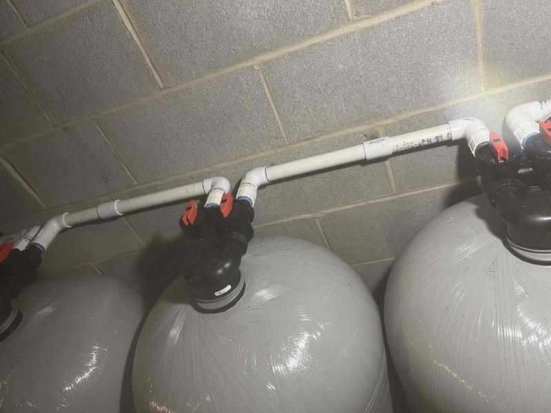 Responded to service call for non-proprietary water treatment system experiencing a cracked chlorinated water line and loud vibrating noise during regeneration cycles. Inspected the PVC distribution piping and multi-tank water conditioning setup, documented the damaged pipe section and mechanical connections for repair recommendations.