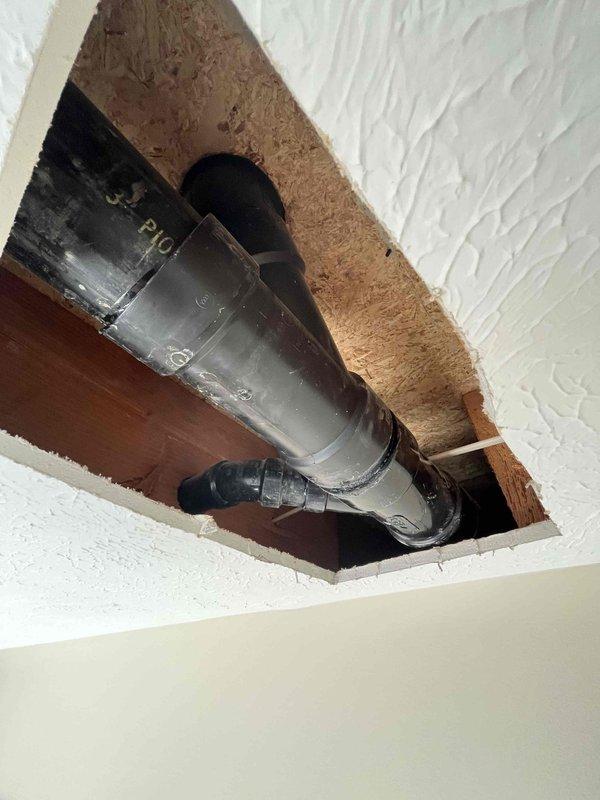 Responded to water leak originating from a 3" PVC wye fitting in the ceiling cavity. Customer had already removed drywall to expose the affected area. Upon arrival, inspected the gray PVC drainage pipe with visible leak at the wye connection point where a black rubber coupling or Fernco boot had failed. Replaced the defective flexible coupling with a proper fitting to restore watertight seal. Additionally addressed a toilet flange issue observed during the service call, completing necessary repairs to ensure proper function and prevent future leaks.