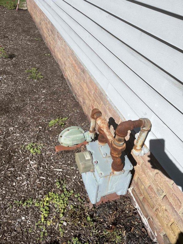 Completed site assessment and provided estimate for rerouting exterior gas line to interior location. Inspection revealed heavily corroded copper piping at exterior gas meter installation with significant oxidation requiring attention. Evaluated existing piping configuration beneath structure, including exposed gas lines secured to wooden joists, and determined optimal routing path for interior relocation to improve system longevity and protection from weather exposure.