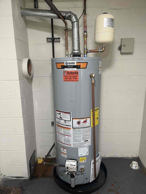 Inspected existing State brand tanked water heater installation and documented current condition with photographs. Unit is properly installed with copper supply lines, expansion tank, drain pan, and appropriate venting system. All safety labels, Energy Guide information, and manufacturer specifications are clearly visible and intact. Installation meets code requirements with proper clearances and support.