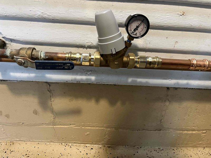 Responded to customer complaint of unusual filling noise occurring in bathroom regardless of which fixture was used. Inspected exterior pressure reducing valve (PRV) assembly and verified proper installation of all components including backflow preventer, water filter, and pressure gauge. Checked interior pressure tank system and confirmed recent installation with operating pressure set at 60 PSI. Tested system operation and verified all plumbing connections were secure with no visible leaks detected at PRV assembly or pressure tank connections.