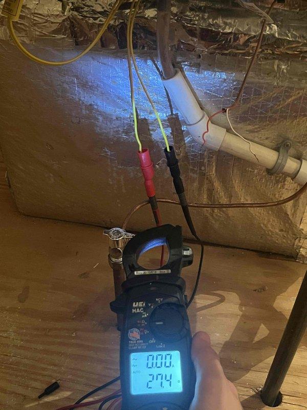 Responded to report of humidifier water valve stuck open causing ceiling leak on unit less than one year old. Upon inspection, discovered significant ice accumulation on evaporator coil assembly and drain pan, indicating drainage issue rather than humidifier valve malfunction. Performed electrical diagnostics using clamp meter to verify system operation and identified underlying condensate management problem. Documented frozen coil condition and ice buildup for warranty consideration given recent installation. Recommended immediate attention to prevent further water damage and restore proper system drainage.