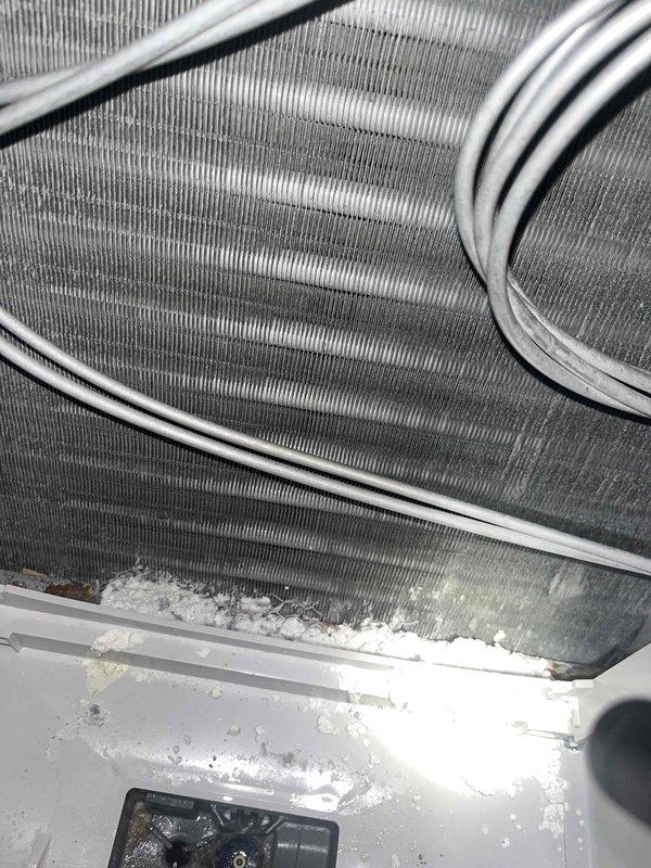 Responded to report of humidifier water valve stuck open causing ceiling leak on unit less than one year old. Upon inspection, discovered significant ice accumulation on evaporator coil assembly and drain pan, indicating drainage issue rather than humidifier valve malfunction. Performed electrical diagnostics using clamp meter to verify system operation and identified underlying condensate management problem. Documented frozen coil condition and ice buildup for warranty consideration given recent installation. Recommended immediate attention to prevent further water damage and restore proper system drainage.