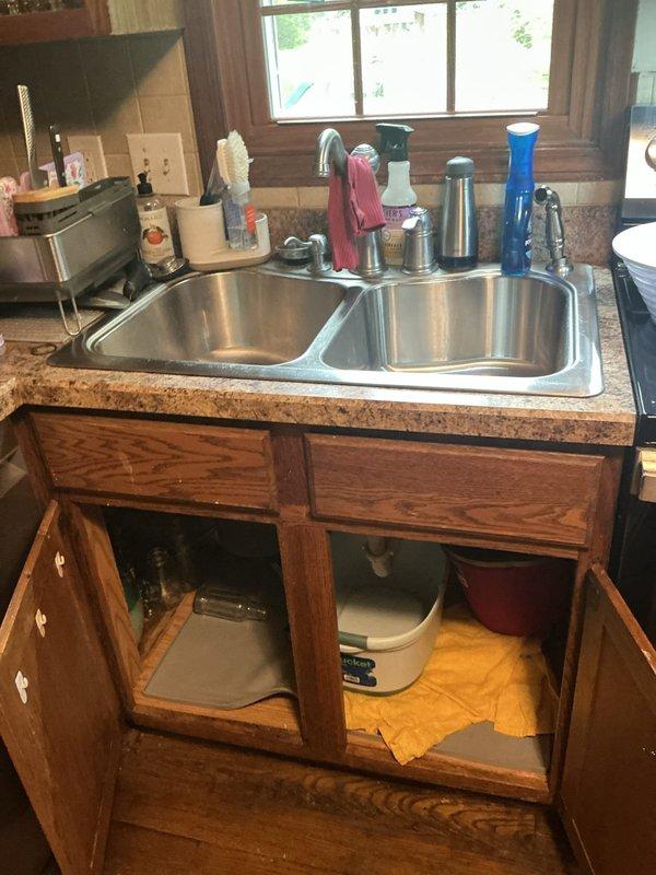 Responded to service call for kitchen sink sprayer repair where homeowner's DIY installation attempt resulted in a leaking hose connection. Assessed existing double-basin stainless steel sink with standard faucet assembly and inspected under-sink plumbing configuration including P-trap, supply lines, and shut-off valves. Provided estimate for proper installation and repair of replacement sprayer assembly, and furnished separate quote for future replacement of existing sink with new 32x22 stainless steel drop-in single basin unit including compatible single-handle faucet with integrated sprayer.